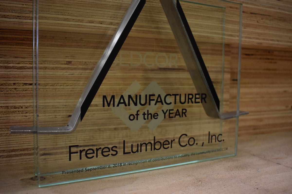 Glass award plaque reading SEDCOR's Manufacturer of the Year: Freres Engineered Wood., Inc. against wood background.