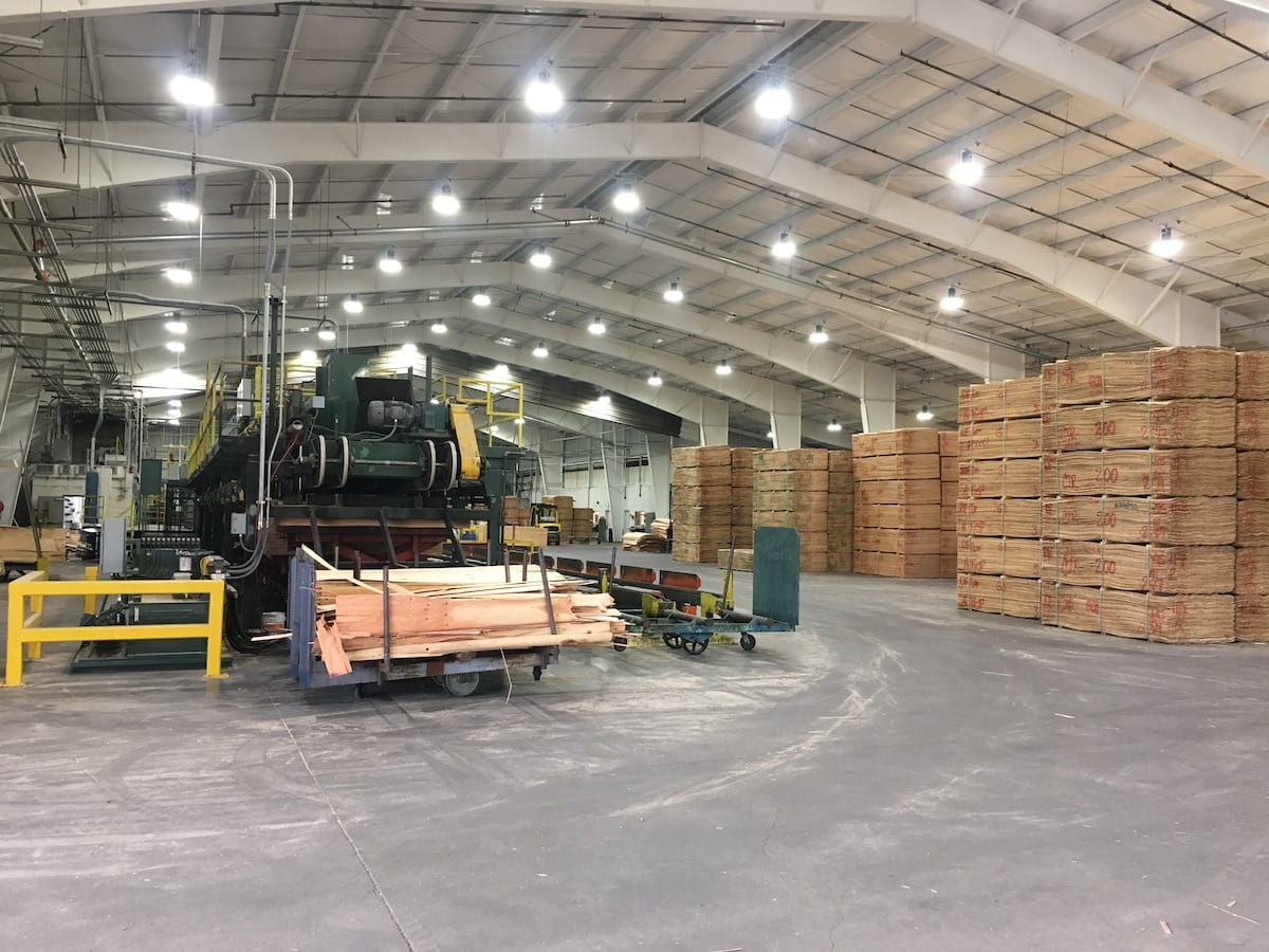 Stacks of plywood and industrial machinery inside the Freres Engineered Wood. manufacturing facility.