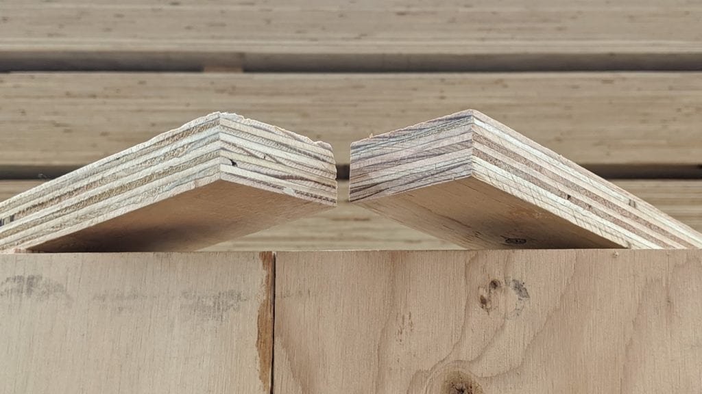 Two cut plywood boards with angled edges, positioned side by side on top of a wooden surface.