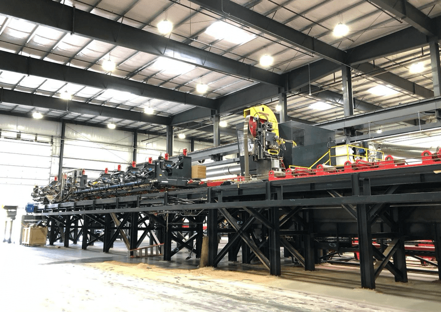 Large industrial machinery inside a spacious factory featuring Mass Ply beam and column structures with bright overhead lighting.